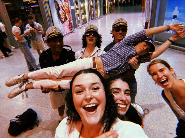 Group of people having fun indoors, one person being held by others.