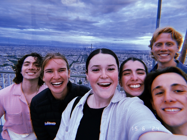Group of friends posing with a cityscape in the background, possibly Paris.