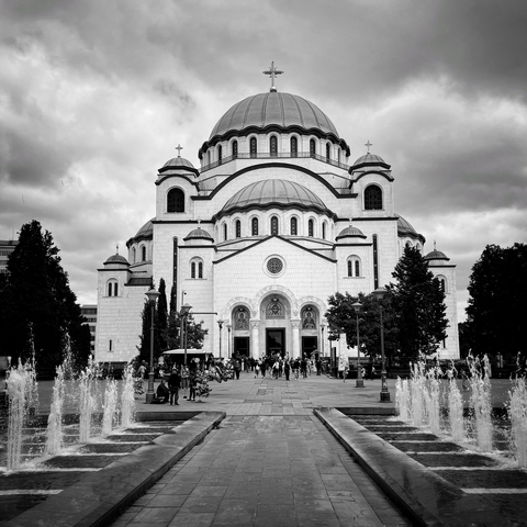 Large white cathedral with multiple domes and fountains in the foreground.