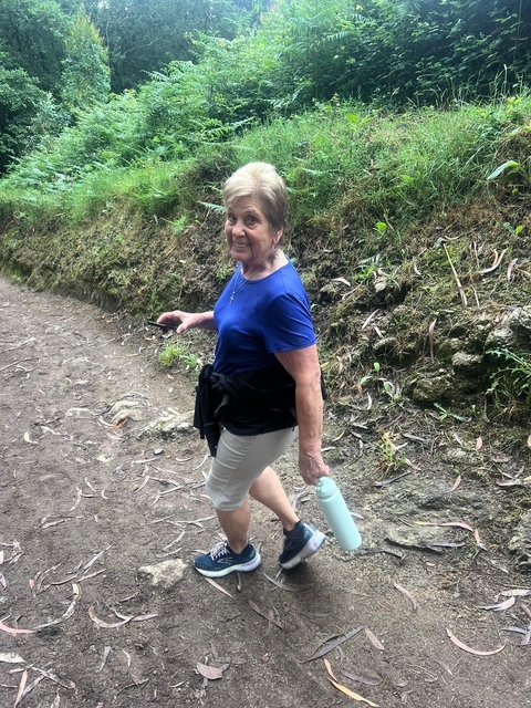 A woman hiking along a natural trail, smiling at the camera.