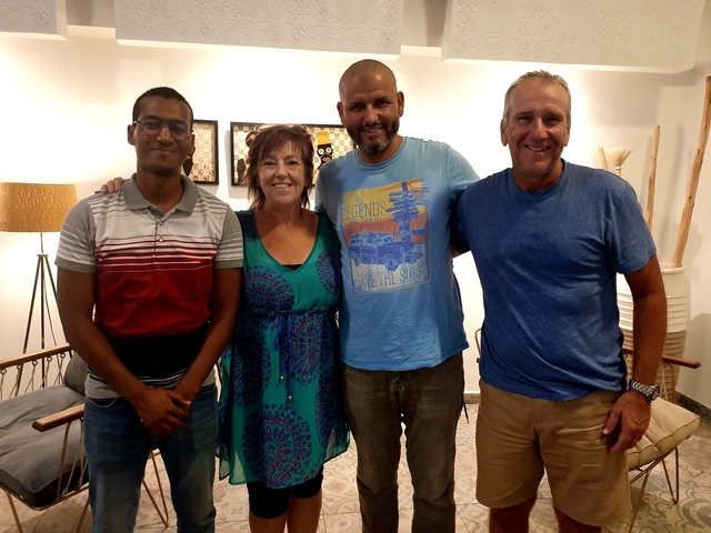 Four people standing inside a room, smiling at the camera.