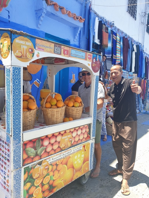 Two people at a fruit stall with baskets of oranges.