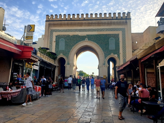 An archway entrance to a marketplace with people walking around.