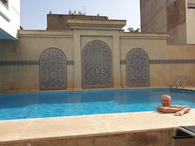 Person relaxing in a swimming pool with ornate tile work.