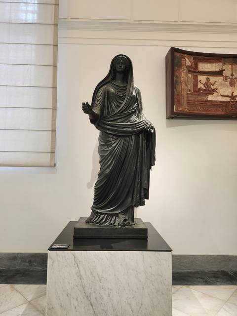 Statue of an ancient figure in a museum setting.