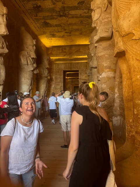 Tourists inside an ancient temple with tall stone columns.