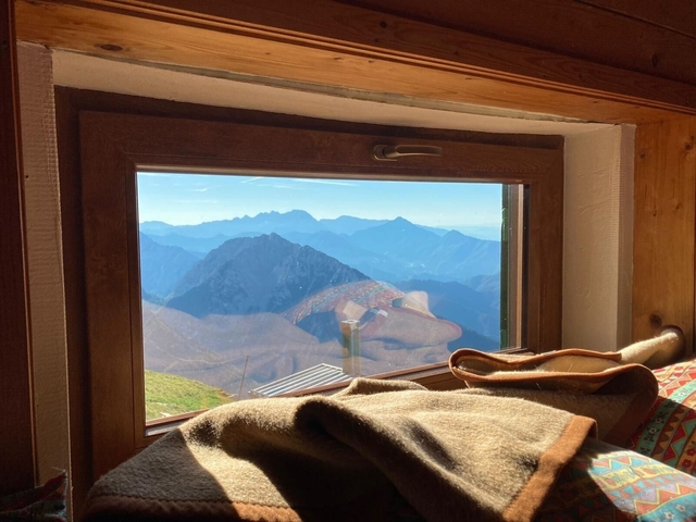 Mountain view through a window with blankets in the foreground.