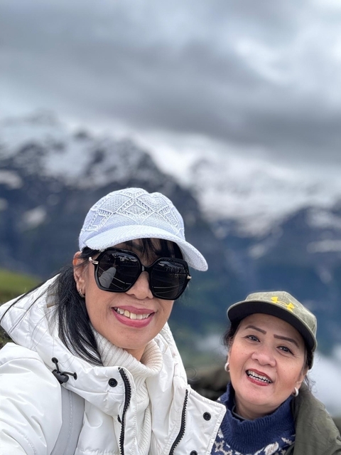 Close-up of two people with snowy mountains in the background.