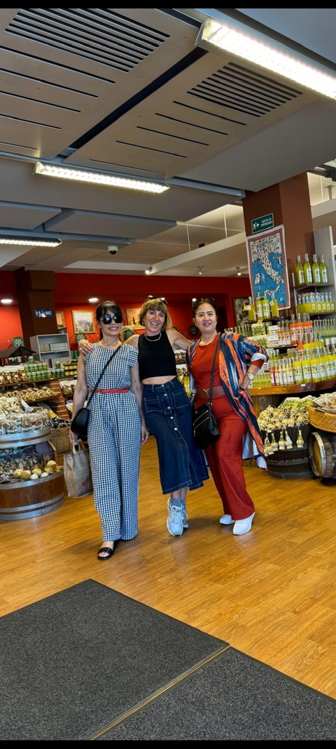 Three women posing inside a shop filled with products.