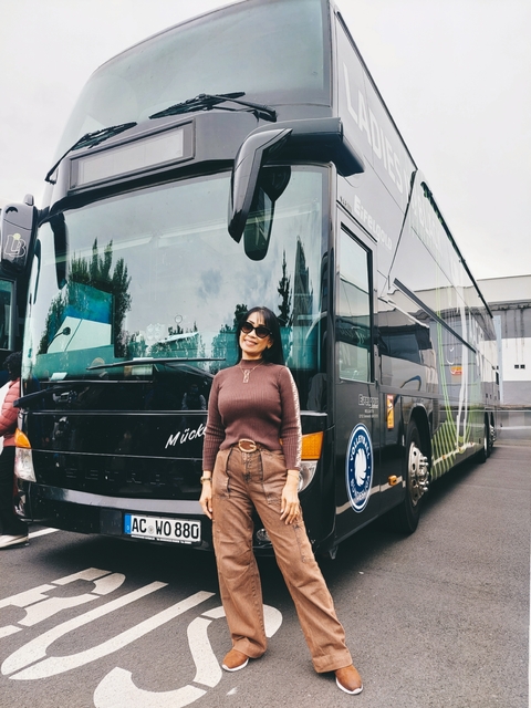 Woman posing in front of a tour bus.