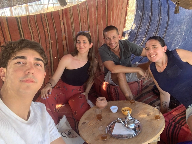       Group sitting on cushions with traditional tea setup.
  