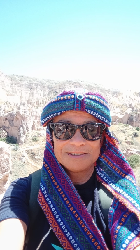 Person taking a selfie with rocky landscape in the background.