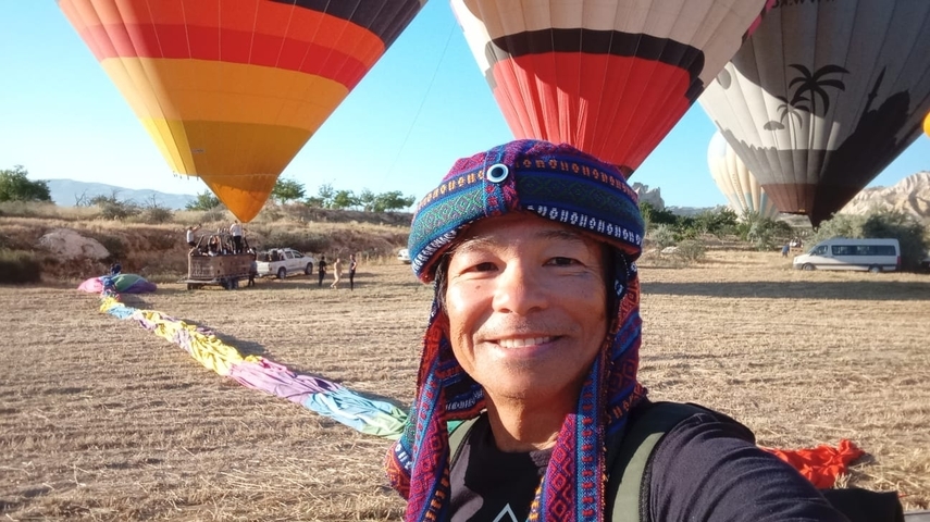 Person standing under colorful hot air balloons on the ground.