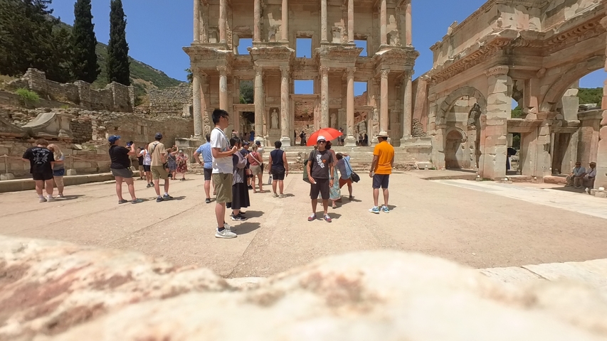 Tourists visiting ancient ruins with large columns.