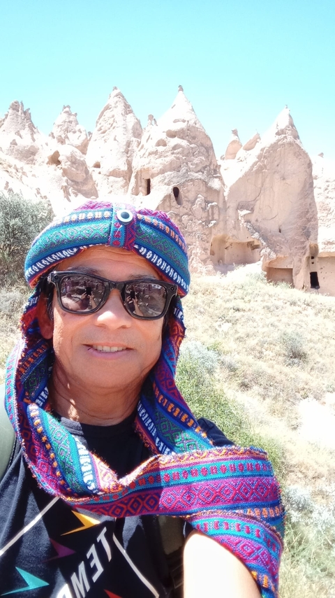       Person taking a selfie with a backdrop of Cappadocia rock formations.
  