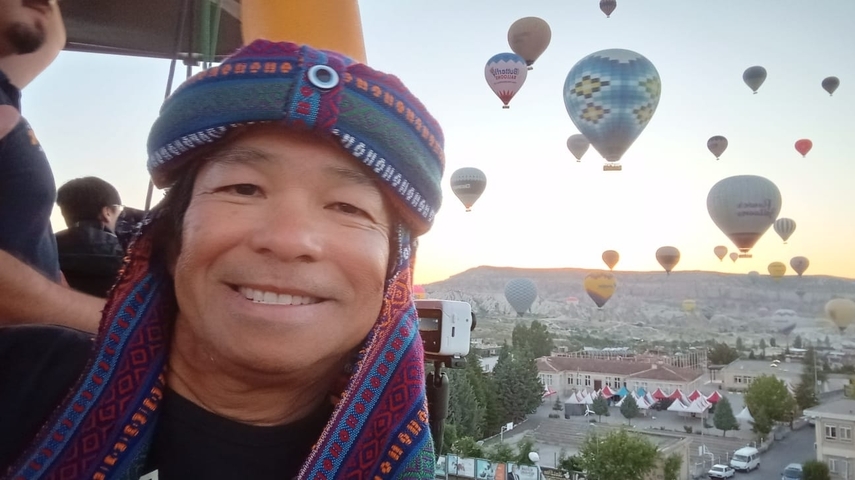 Person in a hot air balloon with other balloons in the background.