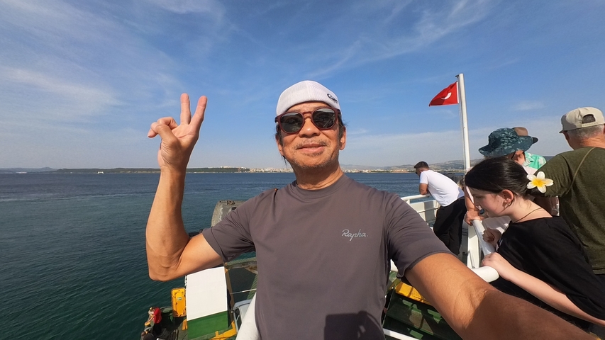 Man taking a selfie on a boat with a view of the sea and a Turkish flag.