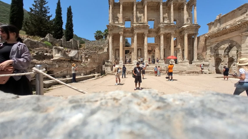 Ancient ruins with people walking around, possibly the Library of Celsus in Ephesus.