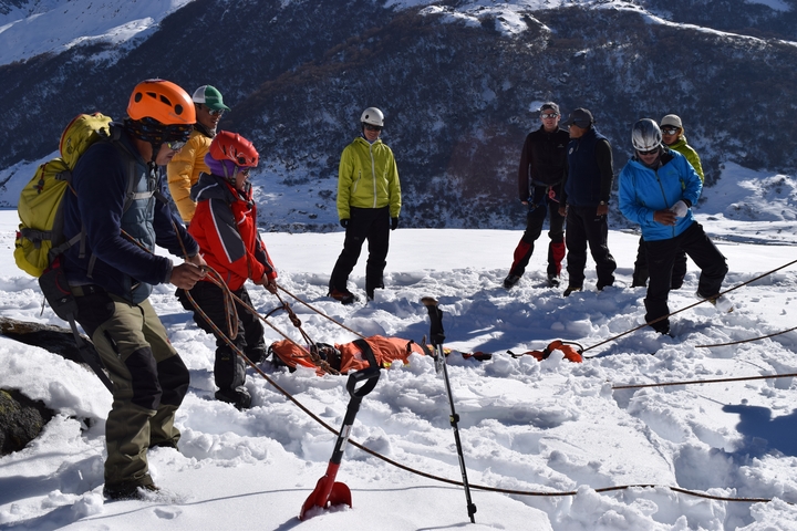       Group of people on a snowy slope practicing mountaineering skills.
  