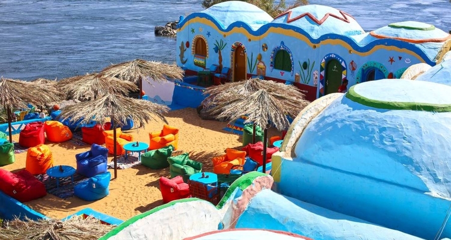       Colorful riverside café with vivid cushions and umbrellas.
  