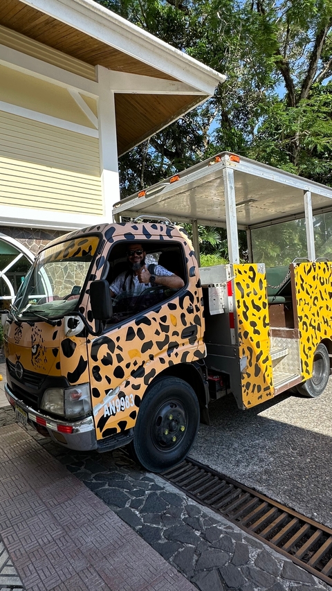 Man thumbs up inside a jeep with leopard print pattern.