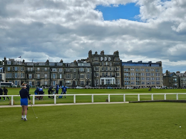 Golf course with historic buildings in the background.