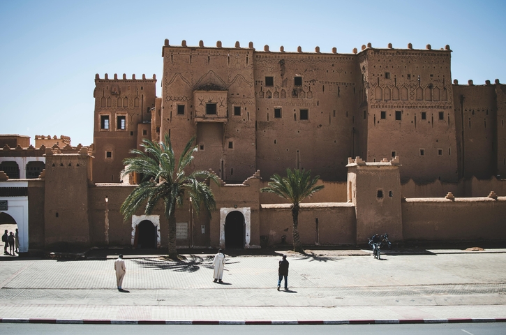Historic kasbah building with people walking.