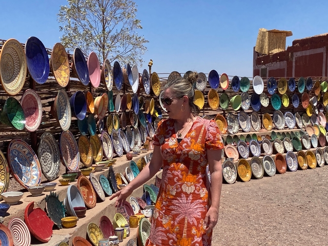       Woman browsing colorful pottery in a market.
  