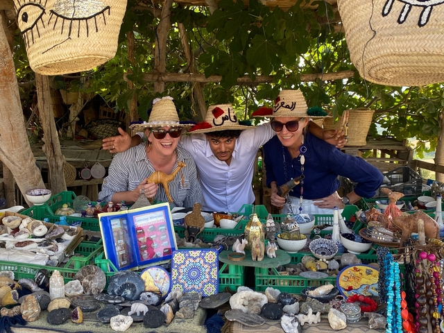       Group of people smiling at a market stall.
  