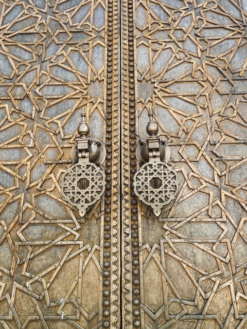       Decorative metalwork details on a large door.
  