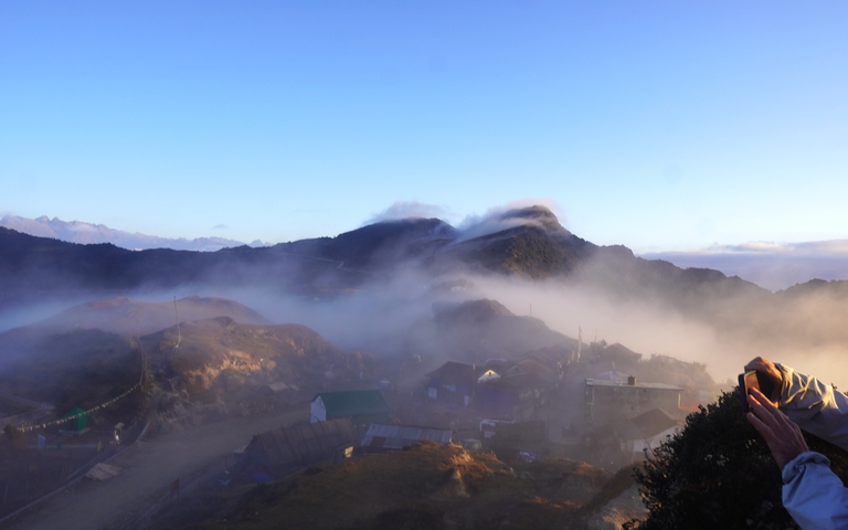       Foggy mountain landscape with a distant village.
  