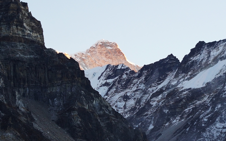       Sunlit mountain peak with surrounding snow.
  