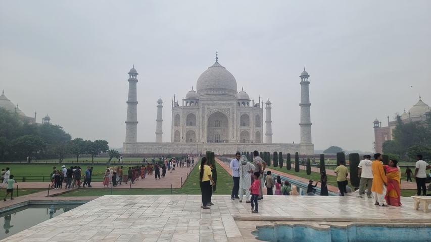       The Taj Mahal with tourists in the foreground.
  