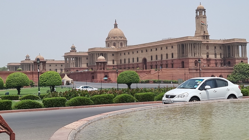 A government building with a car passing in front.
