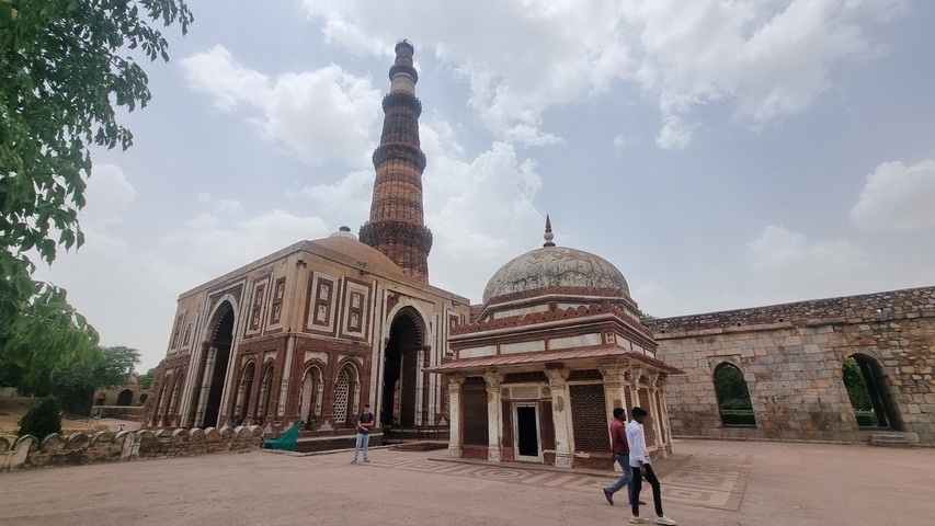 Tourists walking around Qutub Minar complex.