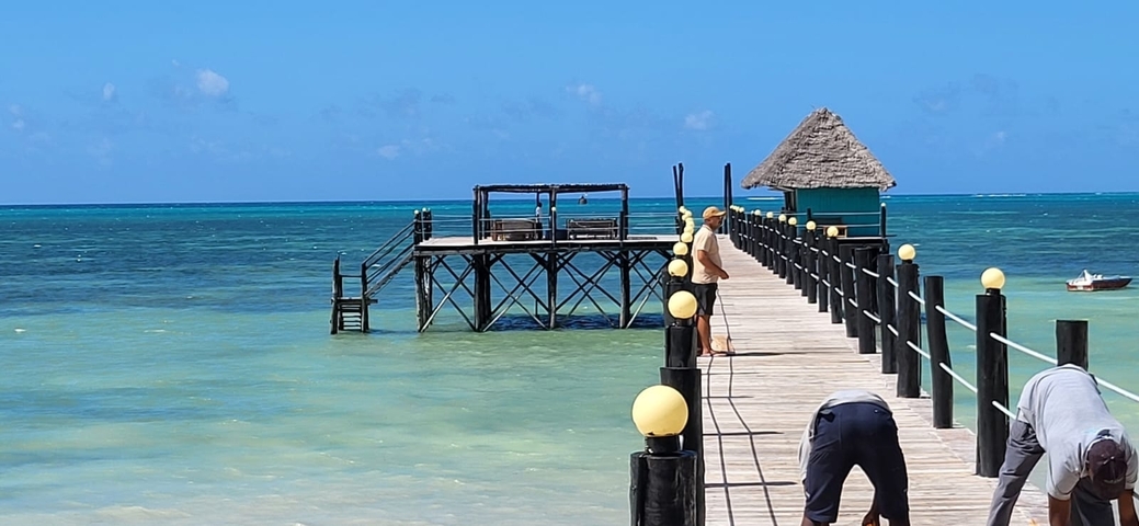 Wooden pier extending into the ocean with clear blue water.