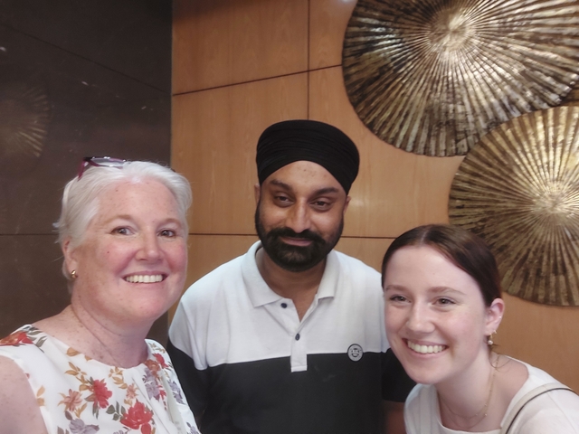 Three people posing indoors with decorative wall features.