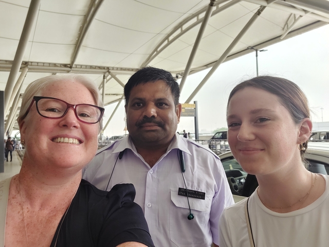 Three people posing at an airport or transportation hub.