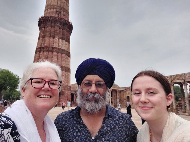 Three people posing in front of a historical tower.