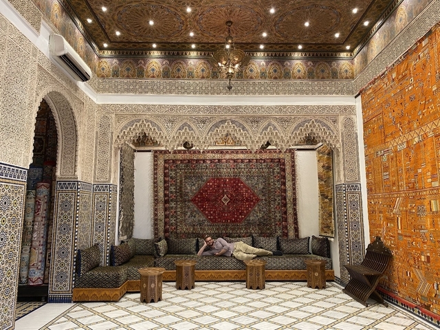 Person lounging in a traditionally decorated room.