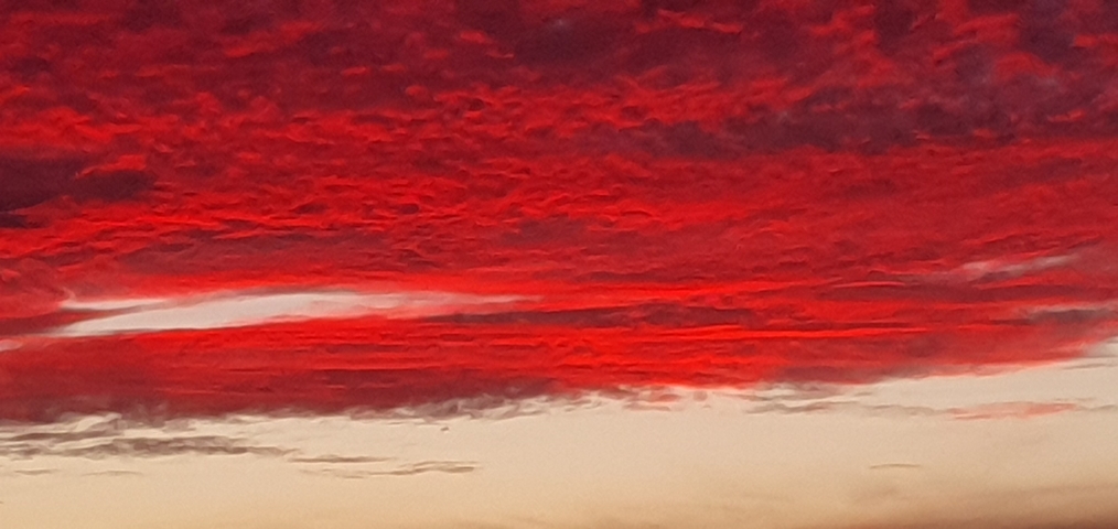 Vibrant red sunset with clouds.