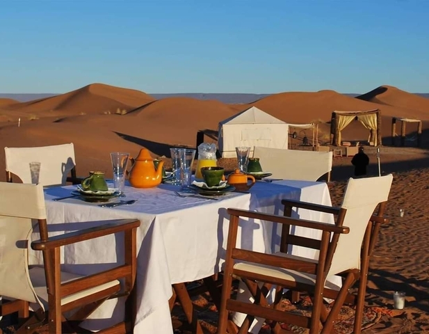 Table set with dinnerware in a desert with sand dunes.