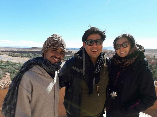 Three people smiling with a desert landscape in the background.