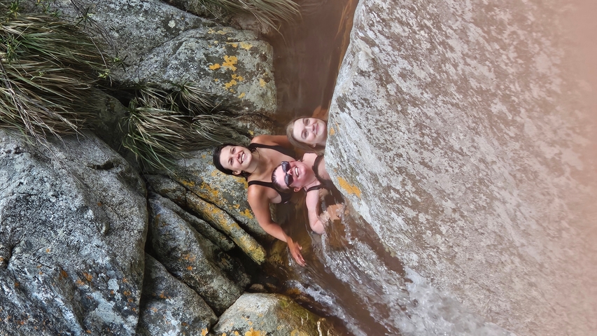       Three people smiling among rocks.
  