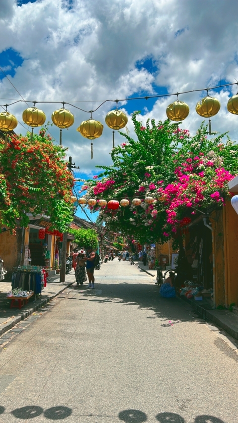 Colorful street market with hanging lanterns and flowers.