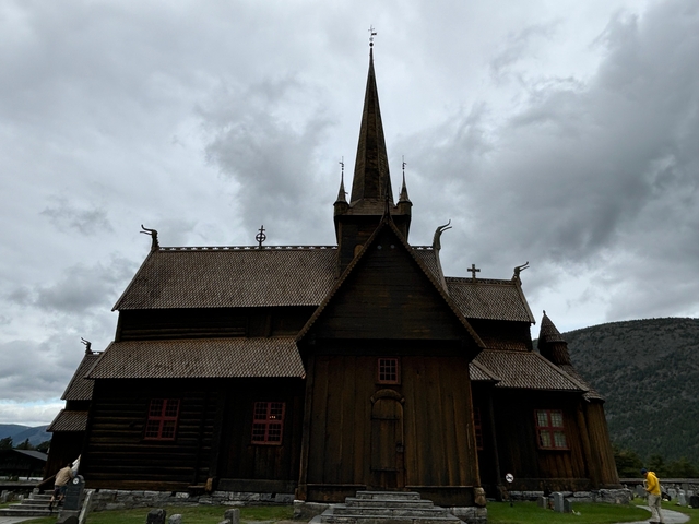       Historic wooden church with a cross and dragons on the roof.
  
