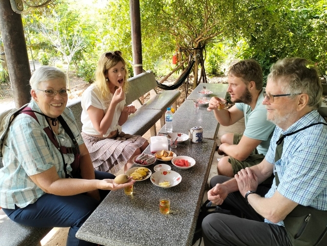 People sitting at a table eating local snacks.