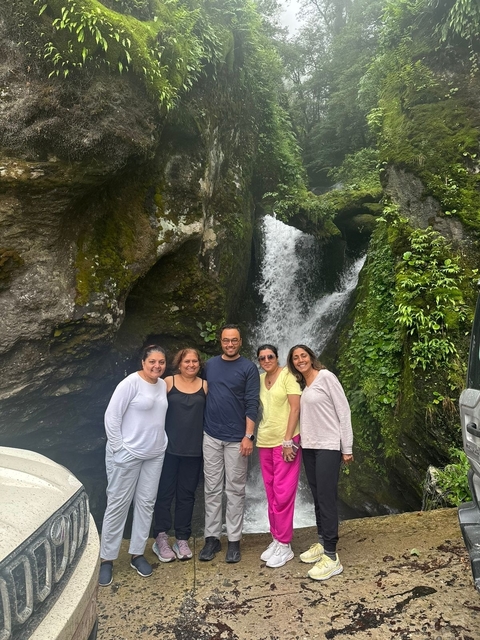       Group of people posing by a waterfall.
  