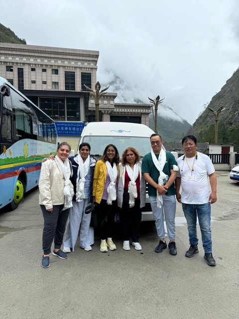       Group of people standing in front of a bus.
  