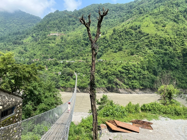       Person crossing a suspension bridge over a river.
  